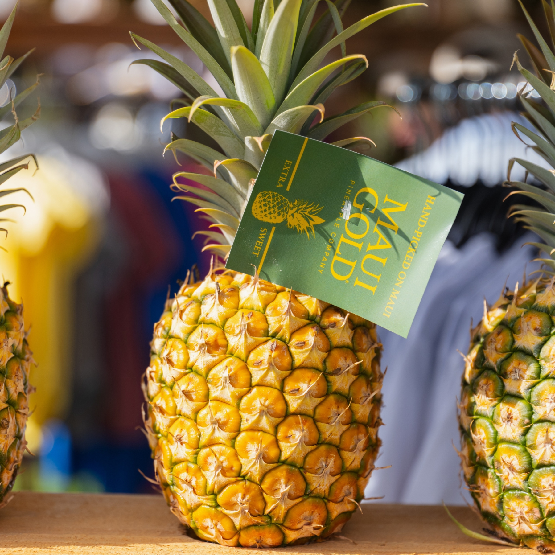 Maui Gold pineapple with tag on display, others blurred in background.
