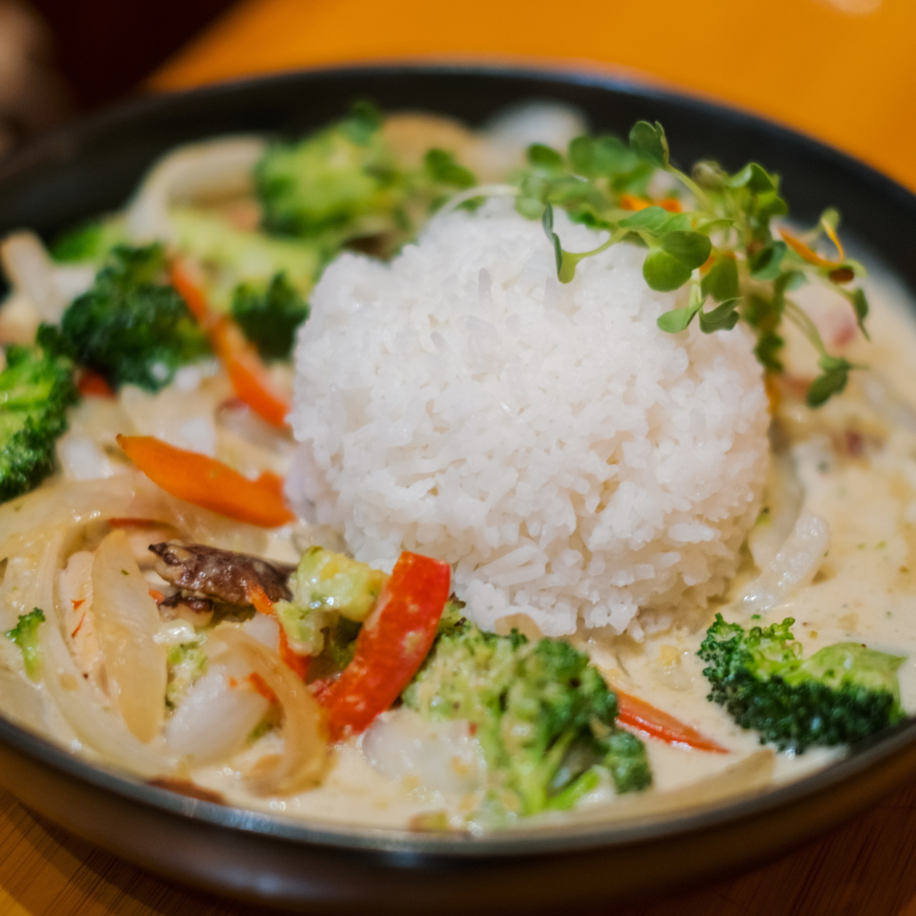A plate of white rice with mixed vegetables in creamy sauce, garnished with greens.