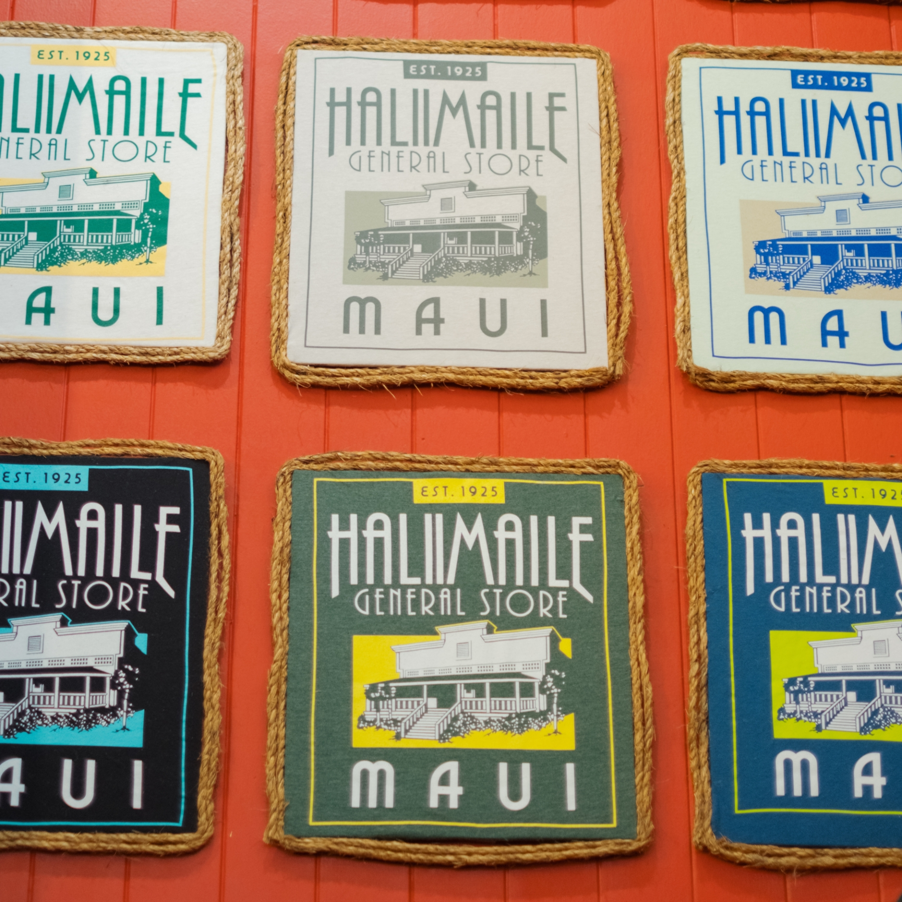 Six colorful signs of Haliimaile General Store, Maui, on an orange wall.